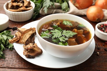 Tasty soup with mushrooms and parsley in bowl on wooden table, closeup