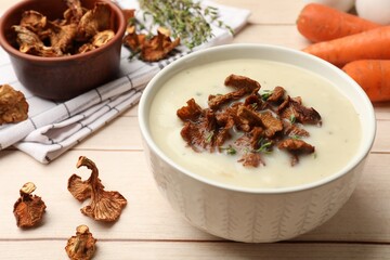 Tasty cream soup with mushrooms and thyme in bowl on light wooden table, closeup