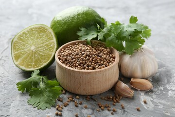 Coriander seeds, fresh cilantro, lime and garlic on grey textured table, closeup
