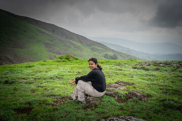Indian woman resting at a windy forest trek viewpoint in Vagamon, Idukki, Kerala

