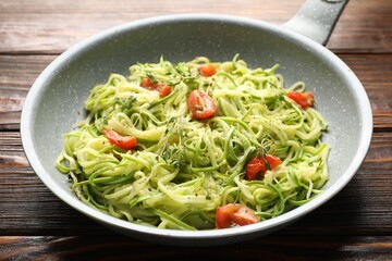 Tasty zucchini noodles with tomatoes and thyme on wooden table, closeup