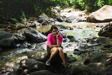 Indian woman relaxing by a forest stream in Vagamon, Kerala during nature hike

