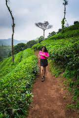 Young Indian woman running through the scenic tea plantations of Kerala, embracing fitness and adventure amidst nature