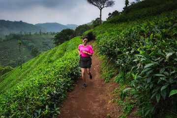 Young Indian woman running through the scenic tea plantations of Kerala, embracing fitness and adventure amidst nature
