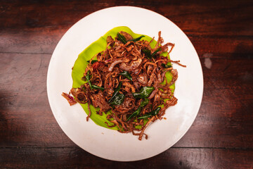 Top view of spicy Kerala-style prawns sautéed with caramelized onions and curry leaves, served on a banana leaf placed on a white plate, showcasing South Indian seafood cuisine.