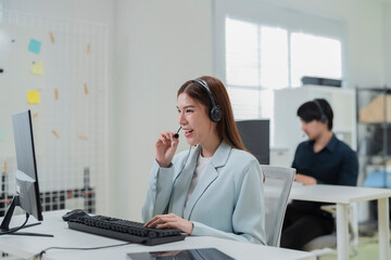 Happy businesswoman with headphones working on PC in call center office, young female technical...