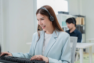 Happy businesswoman with headphones working on PC in call center office, young female technical...