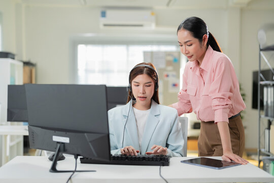 Cheerful mature coworkers and confident operators cooperating on customer cases in call center, female customer service workers talking with supervisor and colleagues about customer service solutions