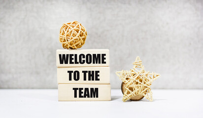 The symbol "Welcome to our team" on the wooden blocks. The background is grey.