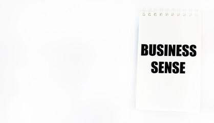 A symbol of business sense. Conceptual words business sense on a notebook. White background, a place to copy