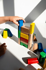 Child building colorful wooden blocks tower in sunlit room