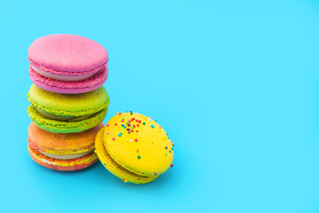 A few brightly colored stacked macarons on blue background.