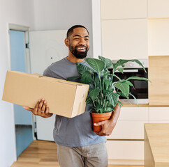 Young black man guy moving into a new modern house, carrying boxes and arriving home. Happy,...