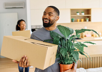 Young black couple moving into a new modern house, carrying boxes and arriving home together....
