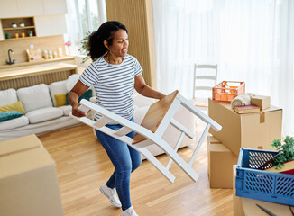 Young black couple moving into a new modern house, carrying boxes, plant and chair and arriving...