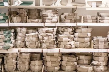 Bulk stacks of neutral ceramic plates, bowls and mugs in retail warehouse display