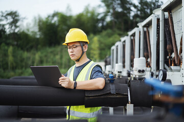 asian engineer working on laptop with  external unit of commercial air conditioning and ventilation...