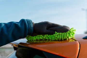 Car detailing session taking place on a sunny day with a focus on polishing the surface using a...