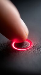 A finger pressing a red circle on a black surface