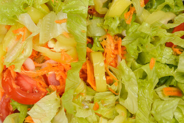 A vibrant close-up of a fresh green salad features crisp lettuce, shredded carrots, bell pepper,...