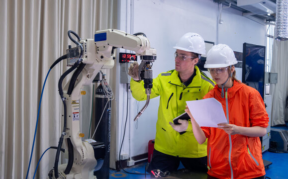 Engineers collaborating on robotics project in a modern workshop setting during daytime hours