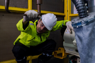 Technician performing maintenance on machinery in an industrial facility during daytime