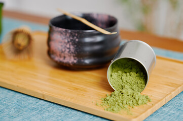 Minimalist tea ceremony setup with black ceramic bowl, bamboo whisk, and matching spoon on wooden...