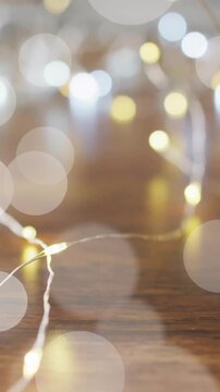 Bokeh lights animation over blurred string lights on wooden surface
