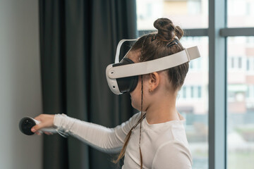 Little girl in virtual reality glasses playing game in room