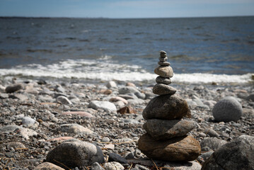 Stacked Stones on a Rocky Seashore with Waves in the Background