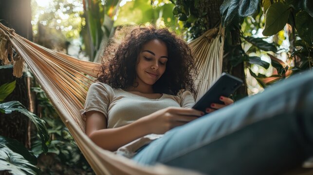 A woman laying in a ham ham with a cell