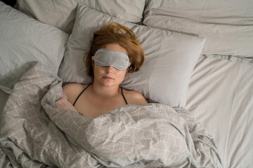 Middle age woman sleeping in bed wearing a sleep mask