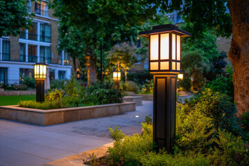 Evening lighting in a modern garden setting with elegant lanterns illuminating the walkway and greenery