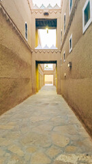 Obraz premium Narrow alleyway in a traditional old town with mud brick architecture in Riyadh, Saudi Arabia