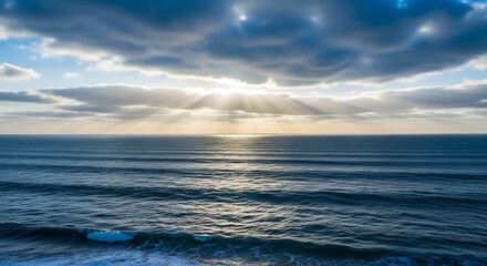 Obraz premium Majestic seascape featuring sunlight beaming through clouds over rippling ocean waters