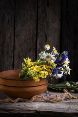Bouquet wildflowers in wooden bowl on wooden background.