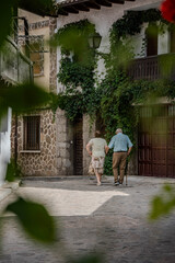 Pareja de abuelos caminando juntos por una calle tranquila de un pueblo tranquilo, Cuevas del...