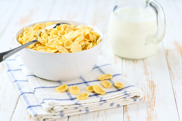 ceramic bowl of tasty corn flakes on a light kitchen table, selective focus.