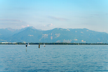 Serene lake view with sailboats and mountains during a sunny day in a tranquil setting