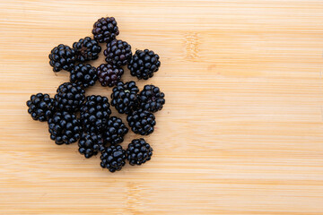 Top-down view of fresh blackberries on a rustic wooden board, showcasing texture, color contrast, and natural arrangement in a minimal food composition.