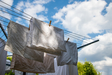 Laundry hanging on a rotary washing line against a bright blue sky with scattered clouds, capturing a fresh, breezy day and everyday domestic life.