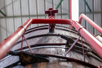 Gros plan sur de grandes cuves en bois alignées à l’intérieur d’une installation artisanale ou industrielle dédiée à la fermentation ou à la production de boissons.