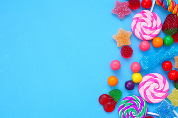 Colorful assortment of candies. Overhead view side border over a blue background.