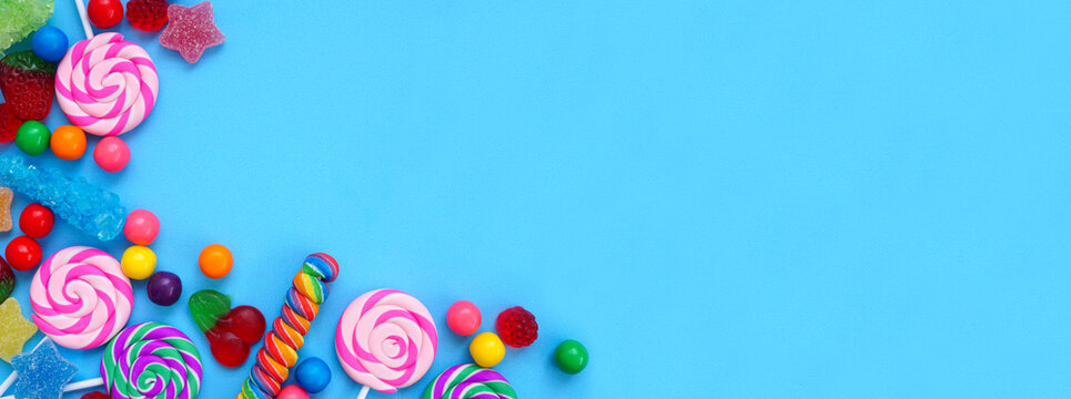 Colorful selection of candies. Top view corner border over a blue banner background.