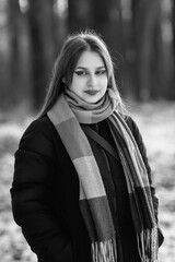 Portrait of a young beautiful long-haired girl in the early winter outdoors. Black and white photo.