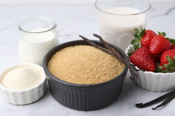 Different ingredients for panna cotta. Milk, sugar, vanilla and strawberries on white marble table, closeup
