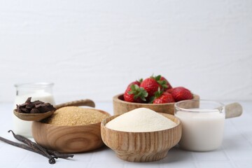 Different ingredients for panna cotta. Milk, sugar, vanilla, chocolate and strawberries on white tiled table, closeup