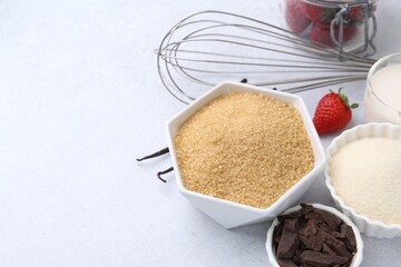 Different ingredients for panna cotta. Milk, sugar, vanilla, chocolate and strawberries on white table, closeup. Space for text