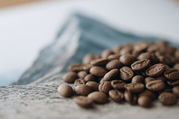 Roasted coffee beans tumble like miniature boulders on alpine backdrop; energizing aroma celebrates International Coffee Day, mountain pilgrimage vibes