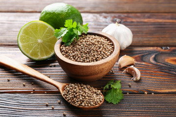 Coriander seeds, fresh cilantro, lime and garlic on wooden table, closeup